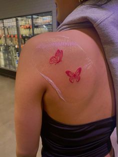 the back of a woman's shoulder with two butterflies on it