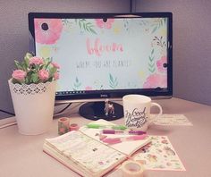 a desktop computer monitor sitting on top of a desk next to a vase with flowers