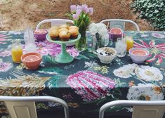 an outdoor table with flowers and fruit on it