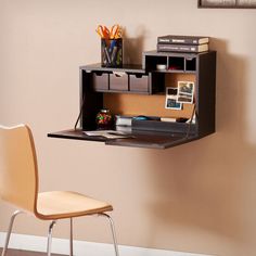 a desk with a chair next to it in front of a wall mounted bookcase