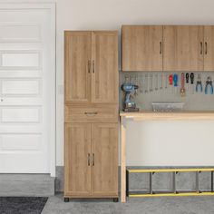 a workbench with tools on the wall and cabinets behind it in a garage