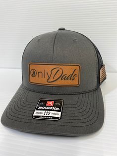 "🎩 Introducing our Richardson 112 Trucker Hat - \"Onlydads\" 🎩 Because subtlety is overrated, right? This leather patch hat is all about celebrating the multi-dimensional nature of dads out there. Wear it proudly, and let the world know you're a responsible adult in public but a wild stallion behind closed doors! 🖤 Available Styles 🖤 These classic combo that's as versatile as your alter ego. 🧢 One Size Fits Most (OSFM) 🧢 Hey, don't worry, we got you covered - literally! Our OSFM size is designed to fit most heads comfortably." Adjustable Flat Bill Dad Hat For Father's Day, Casual Snapback Hat With Flat Bill For Father's Day, Casual Flat Bill Snapback Hat For Father's Day, Adjustable Dad Hat For Father's Day, Father's Day Casual Adjustable Snapback Hat, Adjustable Trucker Hat With Curved Brim For Father's Day, Adjustable Snapback Hat For Father's Day Outdoor, Casual Outdoor Baseball Cap For Father's Day, Brown Outdoor Hats For Father's Day