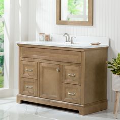 a bathroom vanity with two sinks and a mirror on the wall next to a potted plant