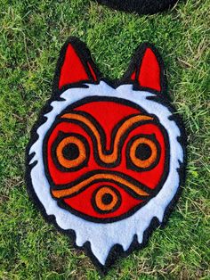 a red and white patch with an animal's face in the center on some grass