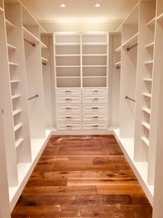 an empty walk - in closet with white shelves and wooden flooring, along with shelving units