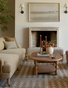 a living room with two couches and a table in front of a fire place