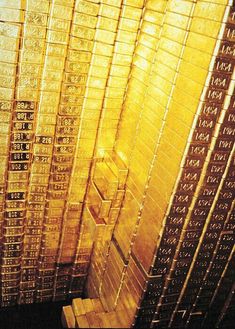 stacks of gold bars stacked on top of each other in front of a wall mounted clock