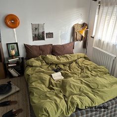 an unmade bed with green sheets and brown pillows