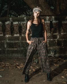 a woman standing in front of a brick wall wearing black pants and a headband