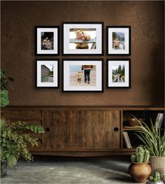 a living room with pictures hanging on the wall and plants in vases next to it