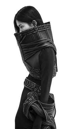 a woman in black is wearing a large piece of clothing and has her head wrapped up