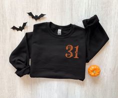 a black shirt with the number 31 on it next to bats and an orange pumpkin