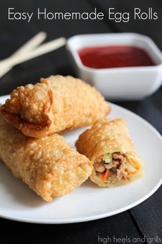 two fried egg rolls on a white plate next to dipping sauce and chopsticks