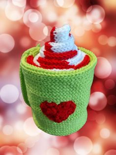 a crocheted cupcake ornament hanging from a string on a red and green background