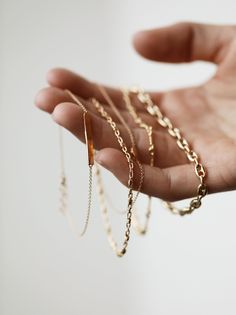 a person's hand holding several gold chains