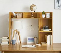 a wooden desk topped with a book shelf filled with lots of books next to a lamp