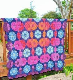 a colorful quilt is hanging on a wooden bench