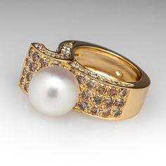 This fantastic ring is topped with one (1), post set, cultured saltwater South Sea pearl. The top face of the ring is accented with forty-six (46), bead set, round brilliant cut champagne colored diamonds. The side faces of the ring are each accented with fourteen (14), bead set, round brilliant cut near-colorless round brilliant cut diamonds. The ring measures 10.6mm at the top, rises 14.7mm above the finger, tapering to 7.2mm wide and 2.0mm thick at the base of the shank. The ring is currently Elegant White Multi-stone Diamond Ring, Formal Multi-stone Pearl Ring In Fine Jewelry Style, Elegant Multi-stone Gold Pearl Ring, Formal White Multi-stone Pearl Ring, Classic Multi-stone Pearl Ring For Formal Occasions, Elegant Yellow Gold Multi-stone Pearl Ring, Formal Yellow Gold Multi-stone Pearl Ring, Elegant Formal Multi-stone Pearl Ring, Diamond Ribbon