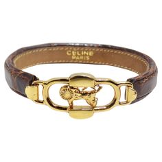 Indulge in equestrian elegance with the Celine 1990s Gold Tone Horse Emblem Leather Bracelet. This brown leather bracelet features a distinctive yellow gold tone horse emblem at the center, creating a super chic and unique accessory with a timeless style that effortlessly transitions from day to night. The combination of rich brown leather and the gold tone horse emblem adds a touch of sophistication to your ensemble. The horse emblem not only symbolizes strength and grace but also exudes a sens Formal Gold Leather Bracelet With Gold-tone Hardware, Elegant Leather Bracelet With Gold-tone Hardware, Elegant Leather Bracelet With Gold-tone Hardware For Formal Occasions, Luxury Leather Bracelet With Gold-tone Hardware, Luxury Leather Bracelet With Gold Clasp, Classic Formal Bracelets With Gold-tone Hardware, Classic Gold-tone Bracelets For Formal Occasions, Luxury Gold Leather Bracelet With Gold Clasp, Luxury Adjustable Bracelets With Gold-tone Logo Plaque