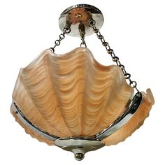 a light fixture hanging from a chain on a white background with an image of a shell in the center