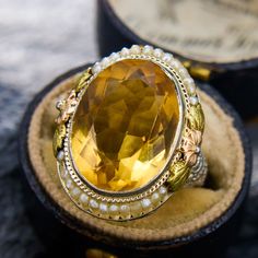 This antique ring features of both the Art Deco and Retro 1940s period. The central oval cut citrine is accented by an engraved border and two sections of seed pearls carefully set onto a wire. The shoulders of the ring are accented with openwork and two-tone floral designs. The ring is crafted in 14k white gold with yellow and rose gold accents, and is currently a size 6. Please note that one seed pearl seems to be missing, but it does not detract from the beauty or symmetric look of the ring. Rose Gold Accents, Antique Ring, Citrine Ring, Seed Pearl, Antique Rings, Floral Designs, Tri Color, Gold Accents, Oval Cut