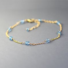 Delicate single strand bracelet created with gemstones in pretty blue color. This bracelet is made with dainty gold filled chain adorned with duos of small, faceted roundels of  London blue topaz. Gems are wrapped with gold filled wire and separated with short sections of dainty,  gold filled chain.  Adjustable from 7.5 to 8.5 inches and it closes with a gold filled lobster claw clasp. Elegant, dainty, trendy, great for layering, bracelet for any occasion. It will make a sweet gift. This style i Blue Beaded Bracelets With Birthstone, Blue Birthstone Beaded Bracelets, Blue Birthstone Round Bead Bracelets, Blue Birthstone Bracelets With Round Beads, Dainty Blue Gemstone Beaded Bracelets, Blue Dainty Gemstone Beaded Bracelet, Blue Dainty Birthstone Bracelets, Blue Aquamarine Gemstone Bracelets, Dainty Blue Gemstone Bracelets