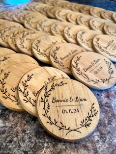 personalized wooden coasters with names and date engraved on the front, sitting on a granite countertop