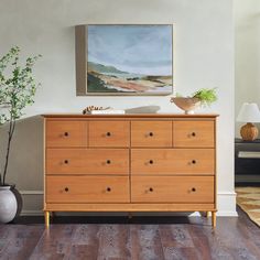 a wooden dresser sitting in a living room next to a painting