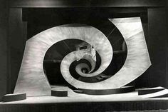 a black and white photo of a sculpture in the shape of a spiral on display