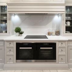 a kitchen with white cabinets and marble counter tops, an oven and range hood in the center