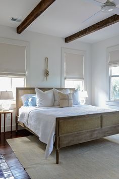 a bed with white sheets and pillows in a bedroom next to two lamps on either side of the bed