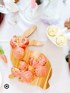 a table topped with lots of food on top of a wooden cutting board next to utensils