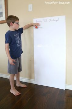 a young boy standing in front of a white board