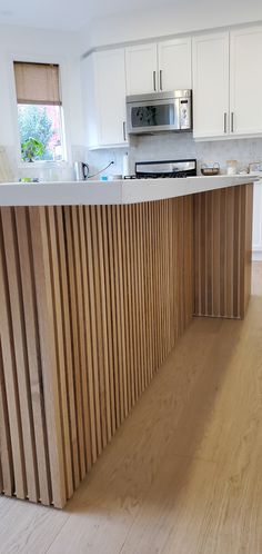 a kitchen with white cabinets and wooden counter tops in the middle of an open floor plan