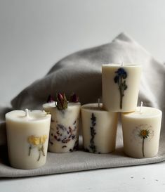 several candles with flowers on them sitting next to a pillow