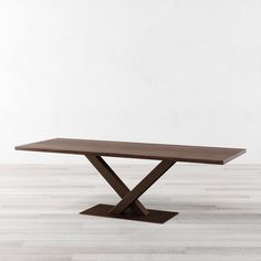 a wooden table sitting on top of a hard wood floor next to a white wall