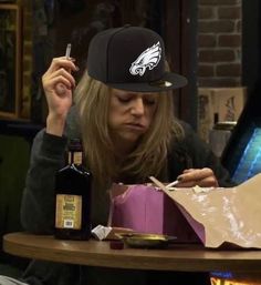 a woman sitting at a table with a bag and bottle