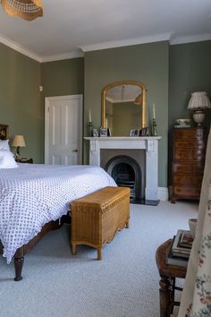 a bedroom with a bed, dresser and mirror in the corner next to a fireplace