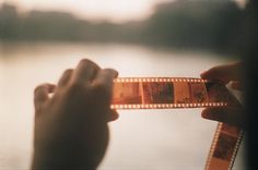 someone is holding up a film strip to take it out of the water with their hands