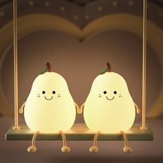 two little lights sitting on top of a table in the shape of pears with faces and hands