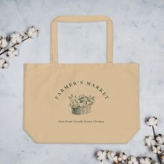 a tote bag sitting on top of a table next to cotton flowers and branches