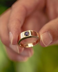 A man holds a custom 14K yellow gold men's engagement ring from Staghead Designs. This signet-style band features a round natural blue sapphire center stone. Luxury Engraved Men's Sapphire Ring, Male Rings With Stone, Navy Blue And Gold Rings, Male Engagement Ring Cool, Affordable Modern Men's Engagement Ring, Affordable Elegant Men's Wedding Ring, Guys Marriage Rings, Luxury Classic Blue Men's Ring, Male Work Engagement Ring