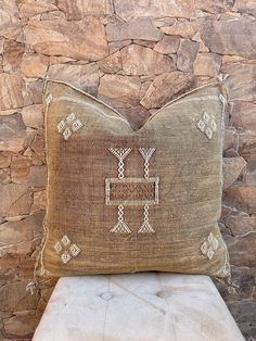 a brown pillow sitting on top of a stone wall