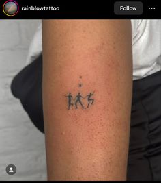 a small tattoo on the arm of a woman with three people holding hands and stars above them