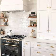 a stove top oven sitting inside of a kitchen next to white cupboards and counter tops