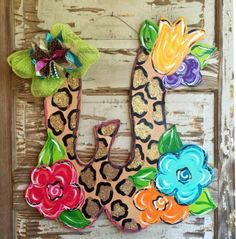 the letter u is decorated with flowers and leopard print, on an old wooden door