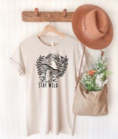 From hiking tees, to camping shirts, to wildflower designs, we love a good nature graphic tshirt. These make perfect gifts for the adventurers and outdoorsy people in your life. We love a challenge, so if you would like something custom, let us know!  THIS LISTING IS FOR ONE ITEM ONLY.  PLEASE READ FULL DESCRIPTION *𝘛𝘩𝘦 𝘥𝘦𝘴𝘪𝘨𝘯 𝘤𝘰𝘭𝘰𝘶𝘳 𝘸𝘪𝘭𝘭 𝘣𝘦 𝘥𝘦𝘧𝘢𝘶𝘭𝘵 𝘣𝘭𝘢𝘤𝘬 𝘰𝘳 𝘸𝘩𝘪𝘵𝘦. 𝘞𝘦 𝘸𝘪𝘭𝘭 𝘤𝘩𝘰𝘰𝘴𝘦 𝘣𝘢𝘴𝘦𝘥 𝘰𝘯 𝘵𝘩𝘦 𝘤𝘰𝘭𝘰𝘶𝘳 𝘰𝘧 𝘵𝘩𝘦 𝘴𝘩𝘪𝘳𝘵 𝘢𝘯𝘥 Spring Outdoor T-shirt With Letter Print, Summer Camping T-shirt With Crew Neck, Cotton T-shirt For Outdoor Activities In Fall, Cotton T-shirt With Funny Print For Outdoor Activities, Casual Mushroom Print T-shirt For Spring, Spring Graphic Print Tops For Outdoor, Casual T-shirt For Outdoor Spring Activities, Casual T-shirt For Spring Outdoor Activities, Casual T-shirt For Outdoor Spring Events