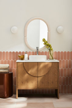 a bathroom with a sink, mirror and stool in front of the wall that has pink tiles on it