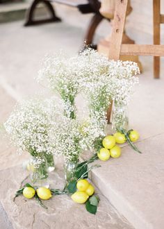 three vases filled with baby's breath flowers sitting on the steps next to a bench