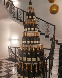 a very tall christmas tree made out of wine bottles in front of a stair case